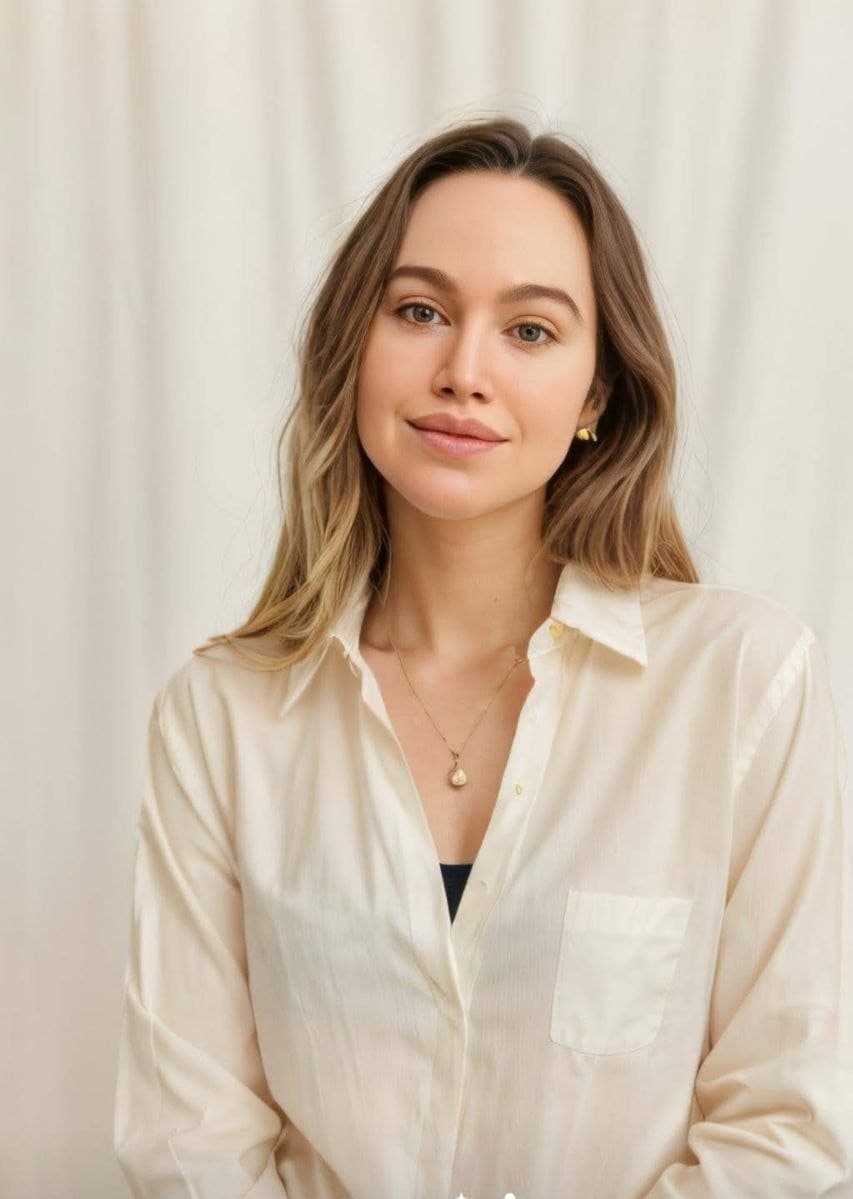 Portrait of Jackie Davies in a cream shirt against a light curtain.